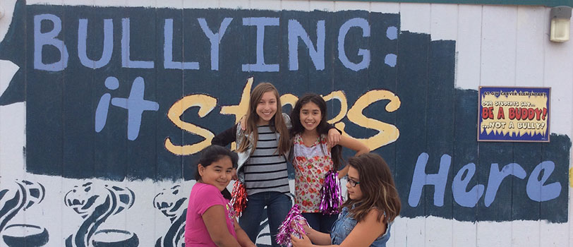 Students pose in front of a sign reading bullying: it stops here